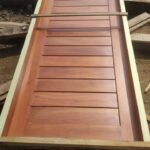 Newly finished solid hardwood louvre door in its frame at the Simba Umeme workshop