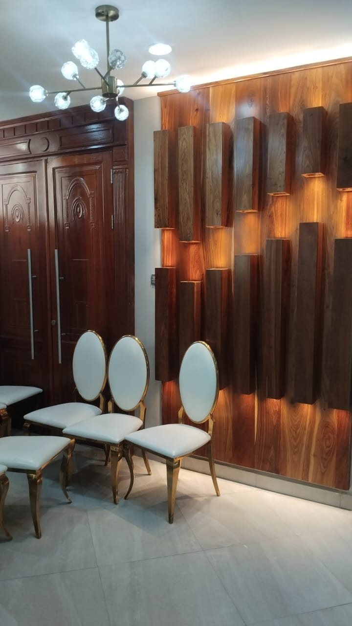 Three-dimensional blocked hardwood feature wall with warm concealed lighting beside carved double doors