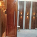 Fluted timber wall panels with brass uplights installed by Simba Umeme