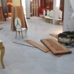 Craftsmen cutting and fitting carved timber panels on site at a Dar es Salaam venue