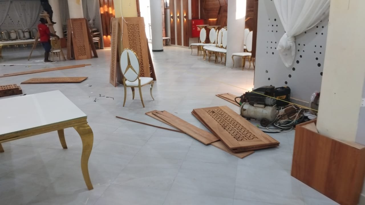 Craftsmen cutting and fitting carved timber panels on site at a Dar es Salaam venue
