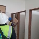 Simba Umeme fitters in safety gear installing timber-framed partitions on site