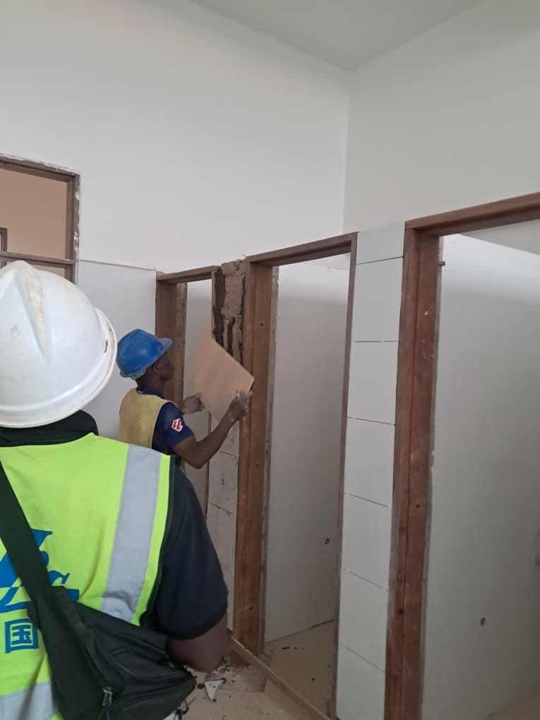 Simba Umeme fitters in safety gear installing timber-framed partitions on site